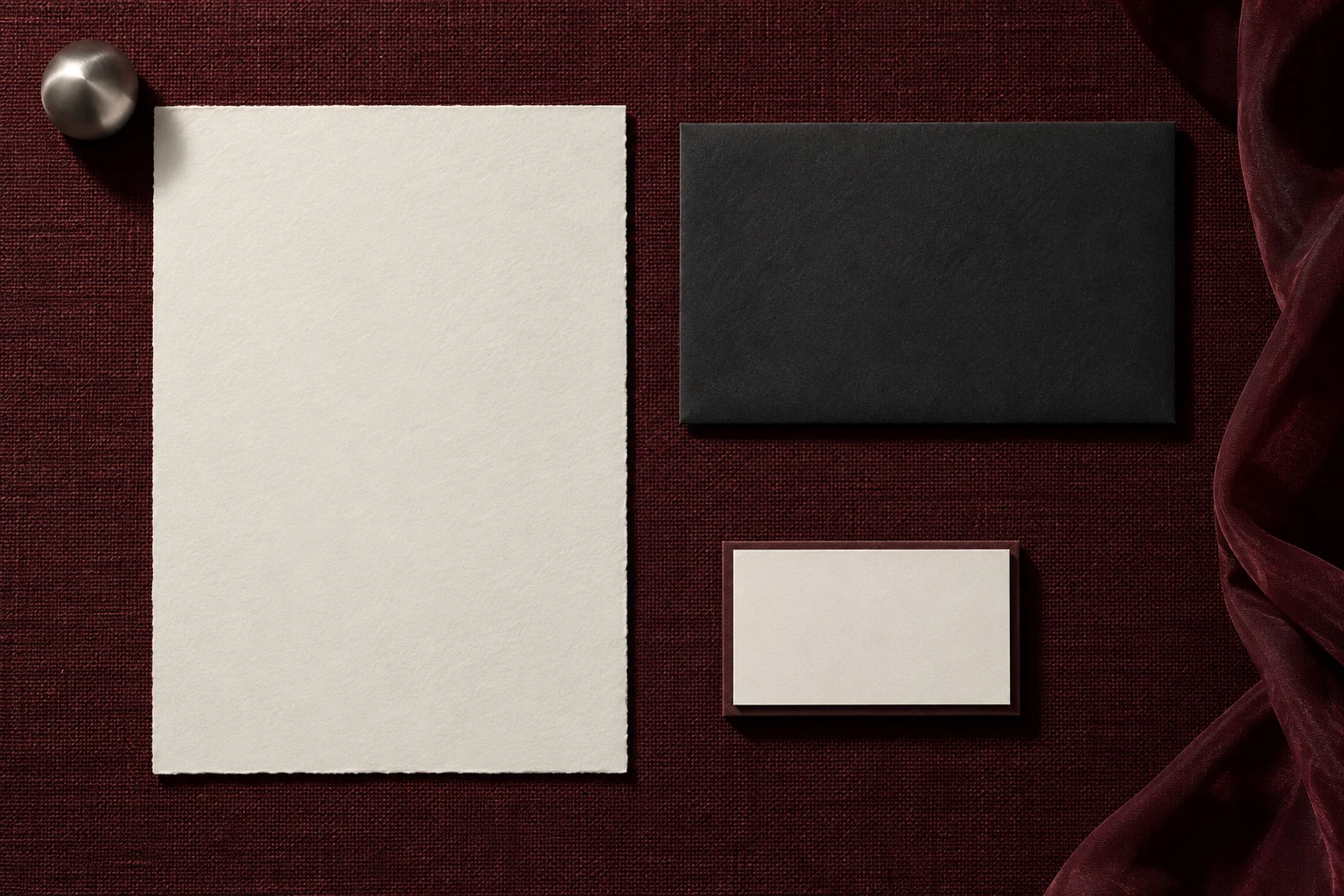Cotton paper and charcoal envelope arranged on wine-colored bookcloth